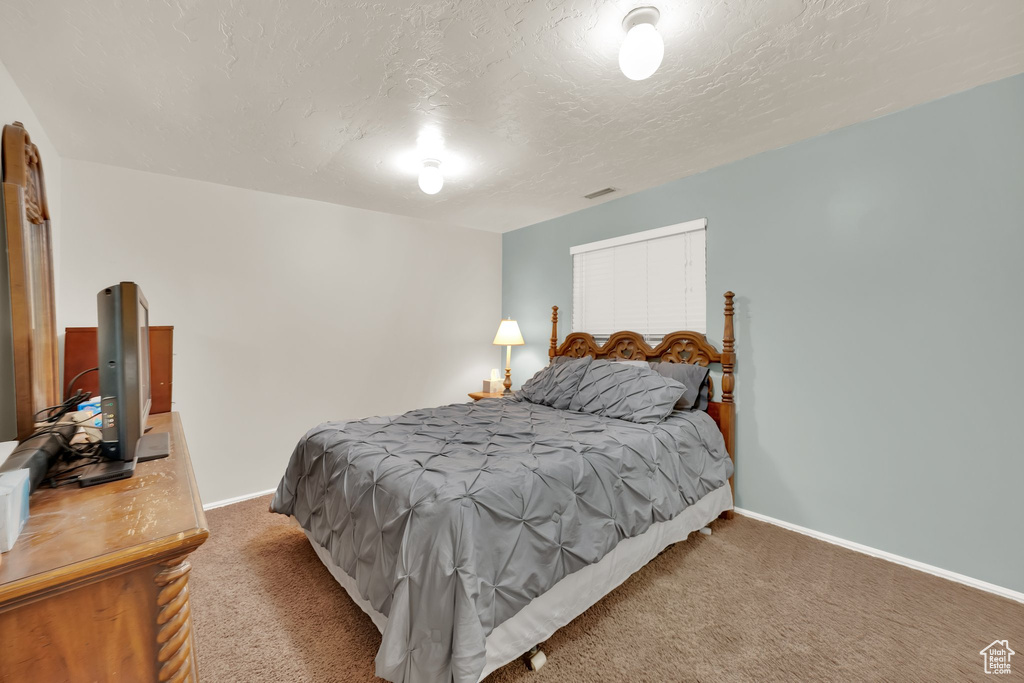Carpeted bedroom featuring baseboards and a textured ceiling