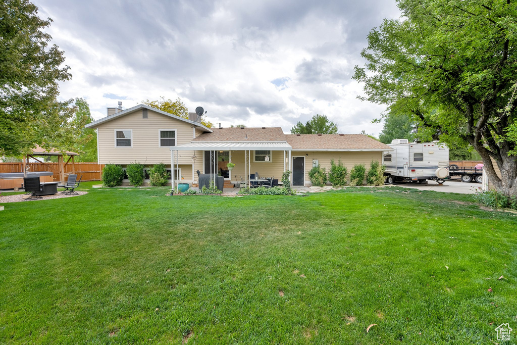 Rear view of property featuring a hot tub and a patio area