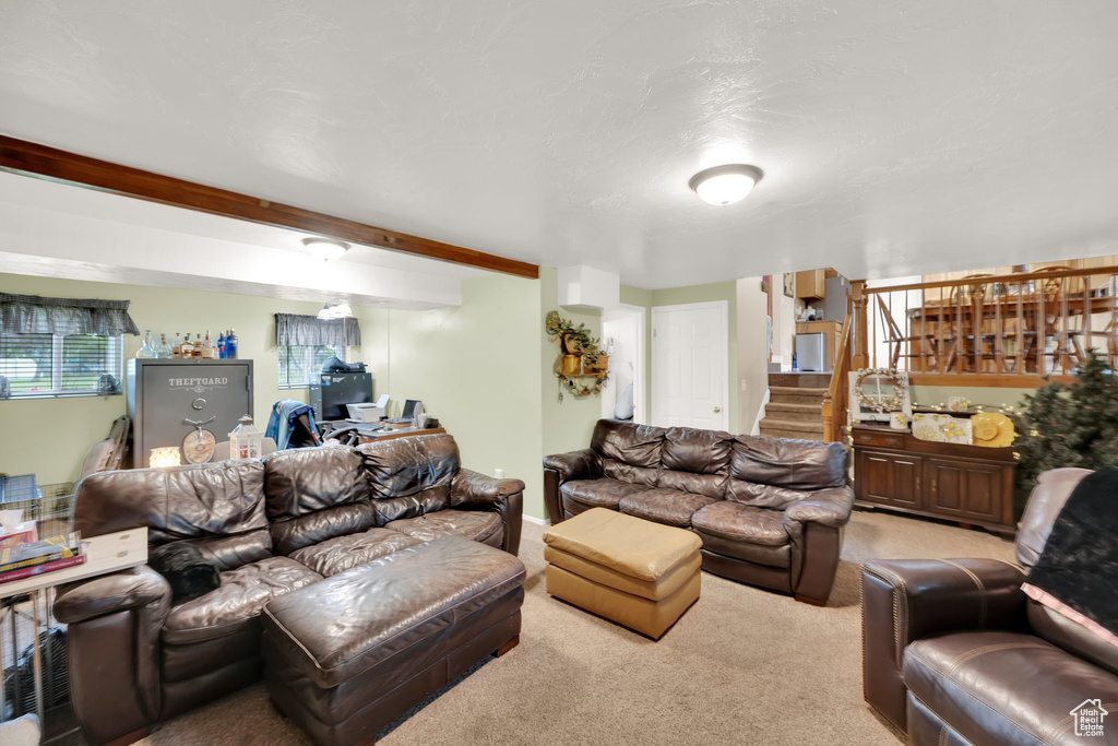Carpeted living room featuring stairs and beamed ceiling
