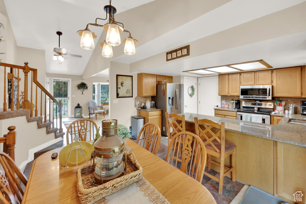 Dining area featuring stairs, a ceiling fan, and vaulted ceiling