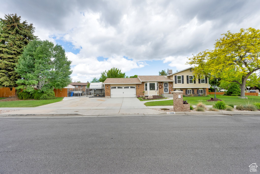 Tri-level home featuring concrete driveway, an attached garage, and brick siding