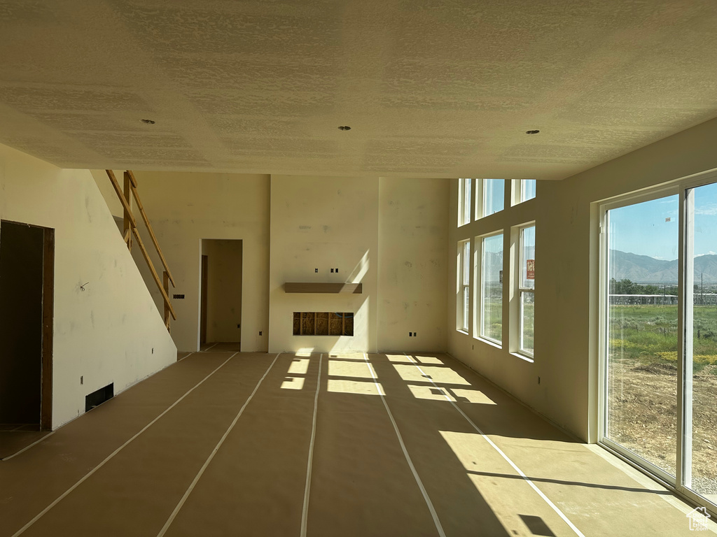 Unfurnished living room with healthy amount of natural light, a textured ceiling, and a mountain view