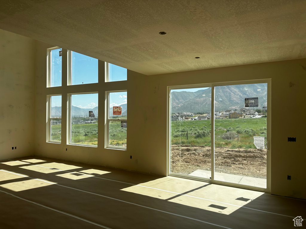 Unfurnished room featuring a mountain view, healthy amount of natural light, and a textured ceiling