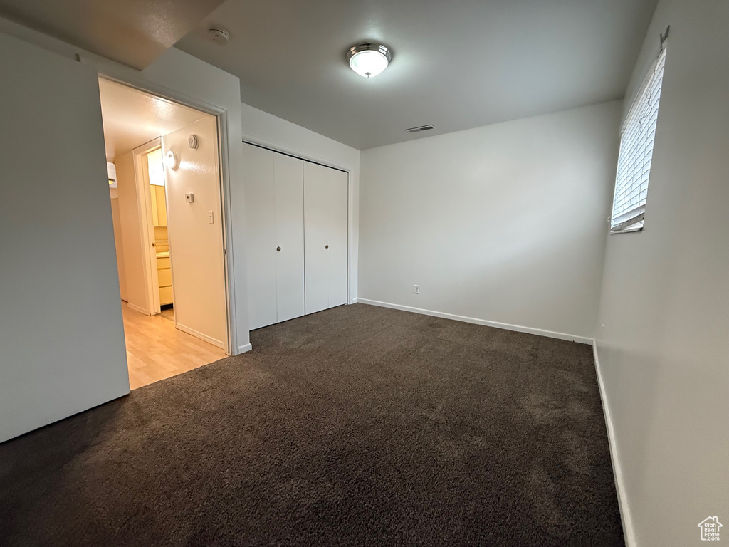 Unfurnished bedroom featuring carpet, baseboards, and a closet