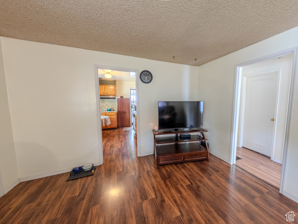 Living room with dark wood-style floors, a textured ceiling, and baseboards