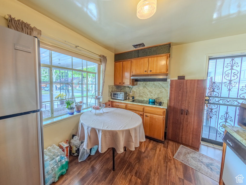 Kitchen featuring freestanding refrigerator, wood finished floors, white dishwasher, decorative backsplash, and light countertops