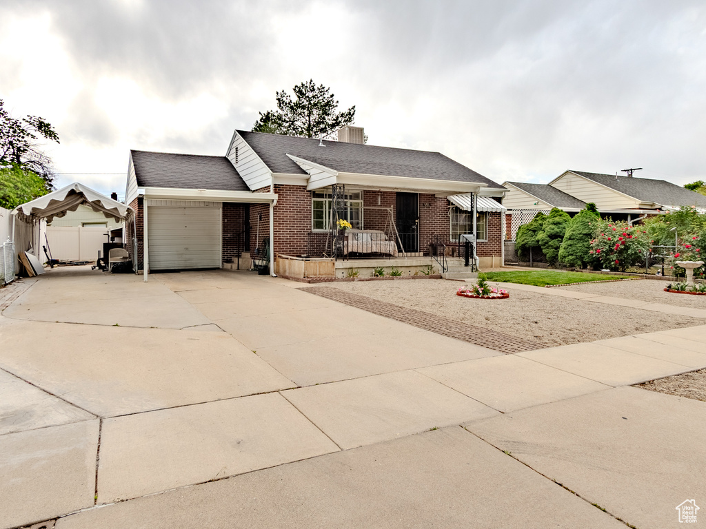 Ranch-style house with brick siding, an attached garage, concrete driveway, roof with shingles, and a chimney