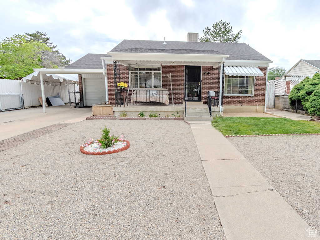 Bungalow featuring fence, brick siding, driveway, and an attached carport