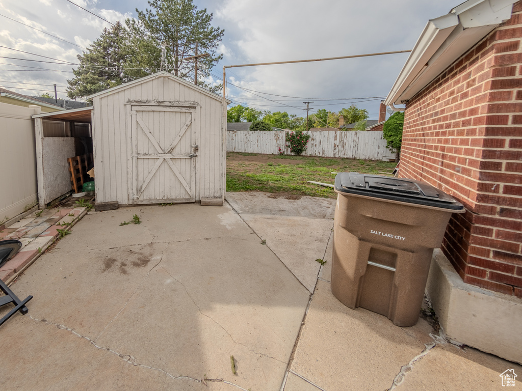 View of patio / terrace featuring fence, a storage shed, and an outdoor structure