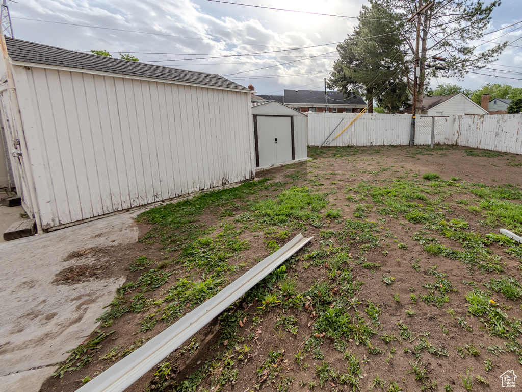 Fenced backyard featuring a shed and an outdoor structure
