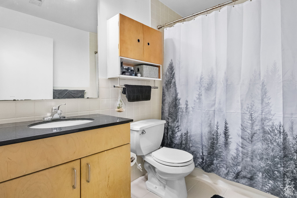 Full bath featuring tile walls, toilet, tile patterned floors, vanity, and a shower with curtain