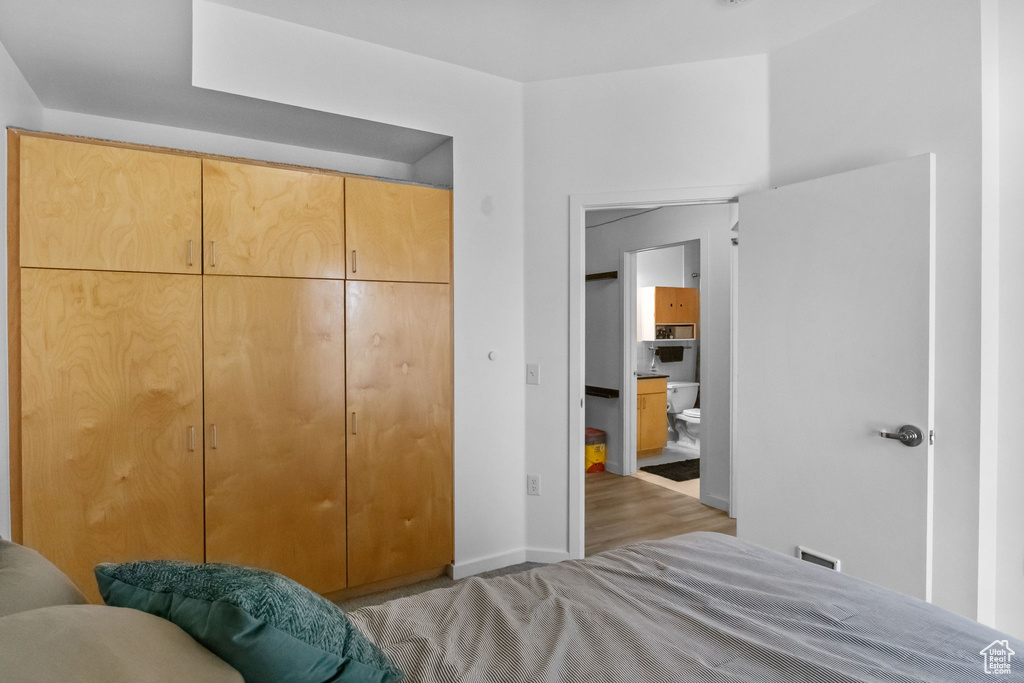 Bedroom with light wood-style flooring, baseboards, and a closet