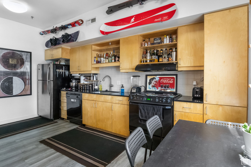 Kitchen featuring black appliances, dark countertops, open shelves, and a sink