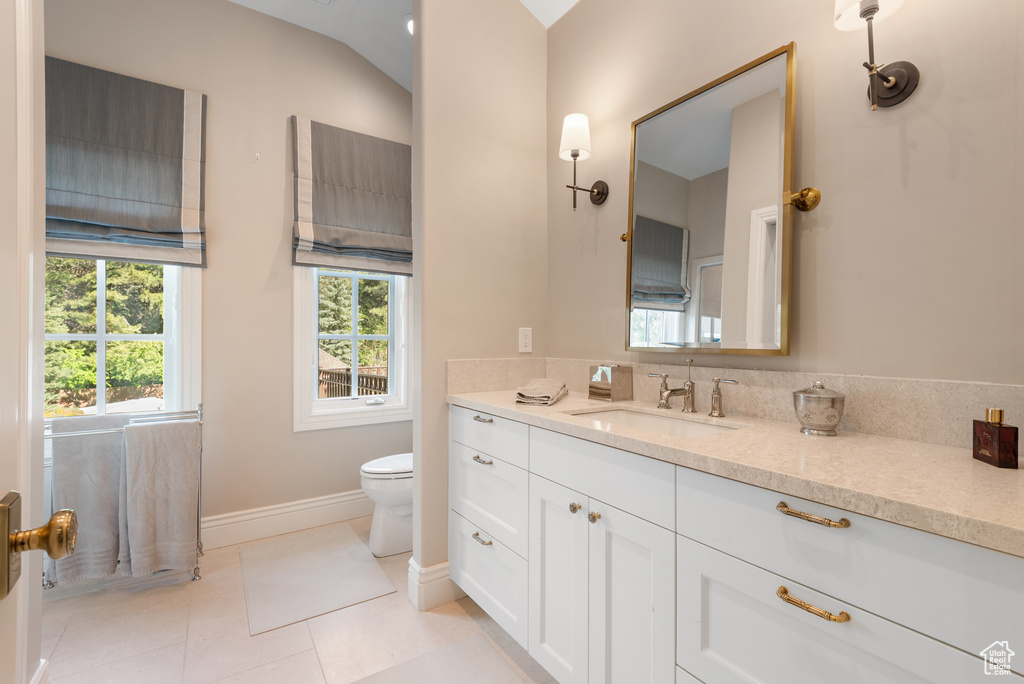 Bathroom with vanity, baseboards, toilet, and tile patterned flooring