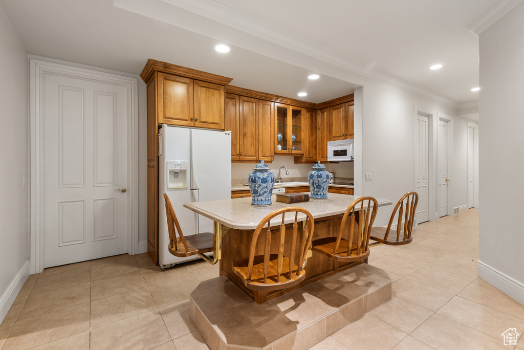 Kitchen with white appliances, brown cabinets, light countertops, recessed lighting, and baseboards