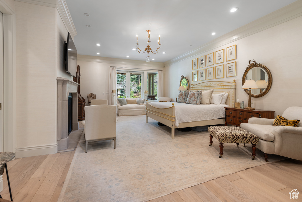Bedroom with wood finished floors, ornamental molding, a chandelier, a fireplace, and recessed lighting