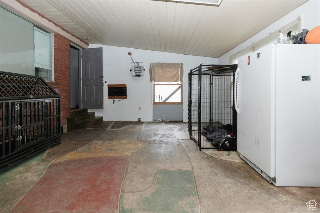 Interior space with freestanding refrigerator and unfinished concrete floors