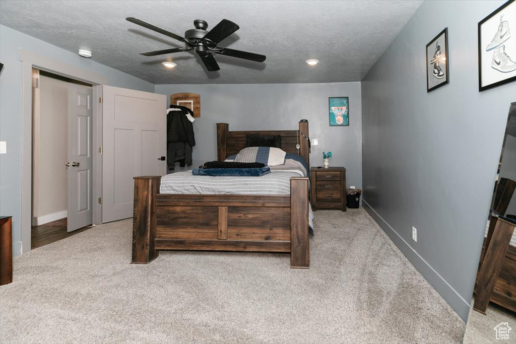 Bedroom featuring carpet floors, baseboards, a textured ceiling, and a ceiling fan