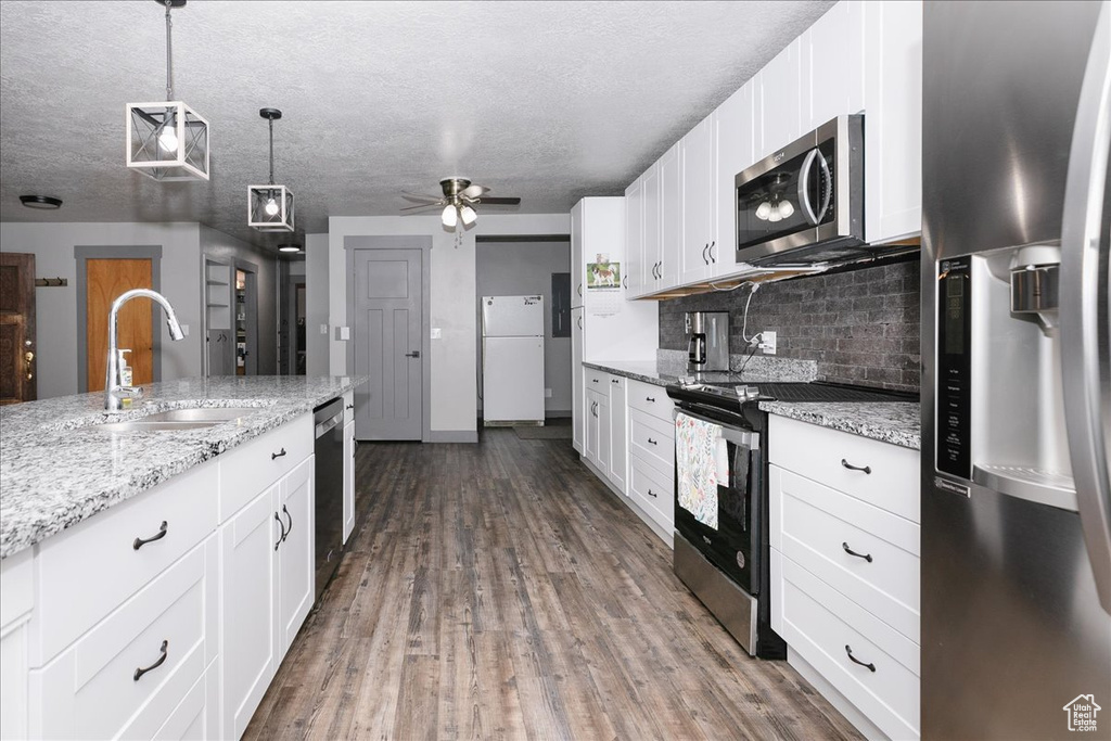 Kitchen featuring stainless steel appliances, a sink, tasteful backsplash, white cabinetry, and a textured ceiling