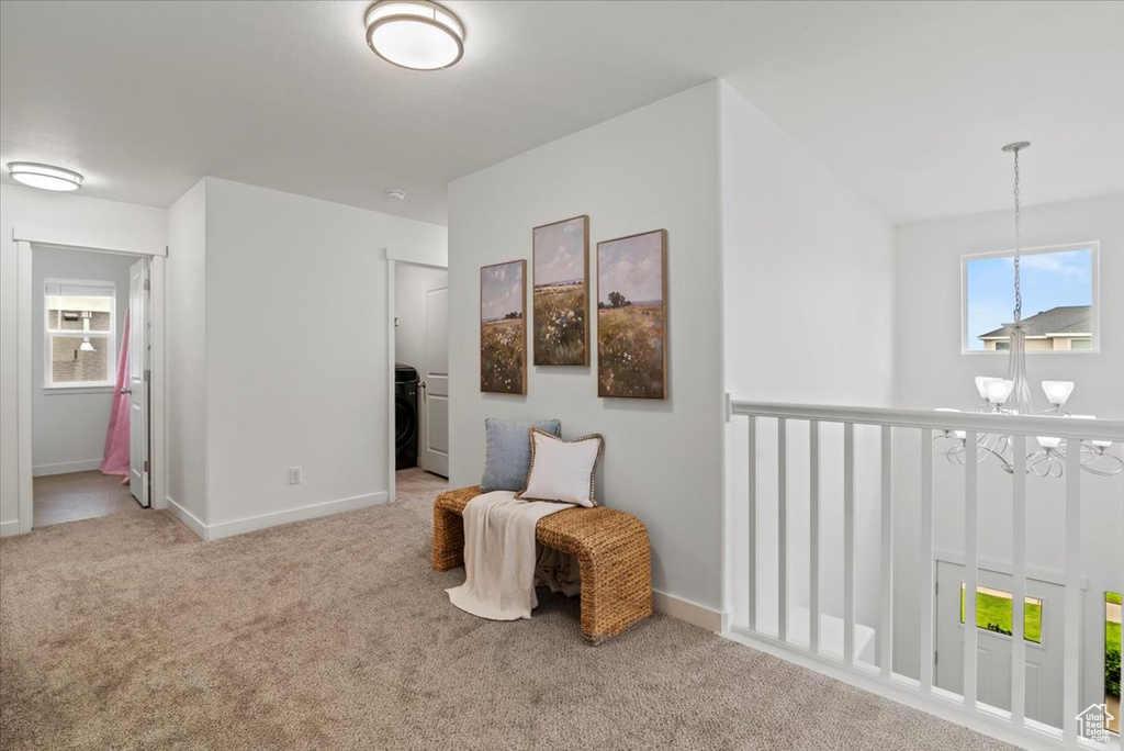 Living area featuring a chandelier, carpet, baseboards, and washer / dryer