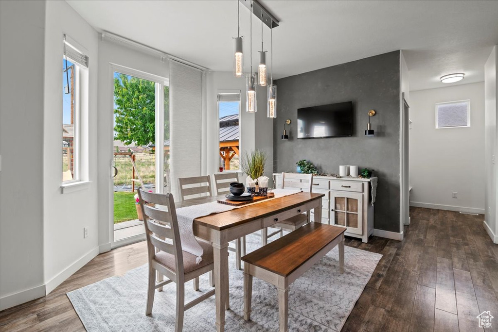 Dining space with dark wood-style flooring and baseboards