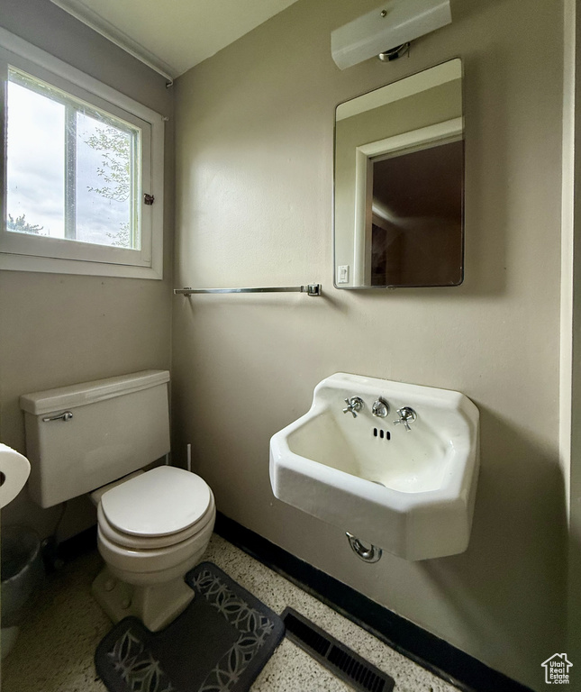 Half bathroom with toilet, speckle patterned floor, and a sink