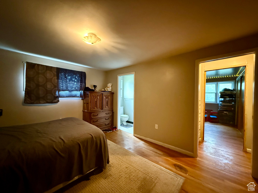 Bedroom featuring light wood-type flooring, ensuite bath, and baseboards