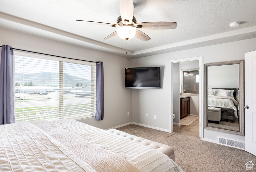 Carpeted bedroom featuring baseboards, a ceiling fan, connected bathroom, and a raised ceiling