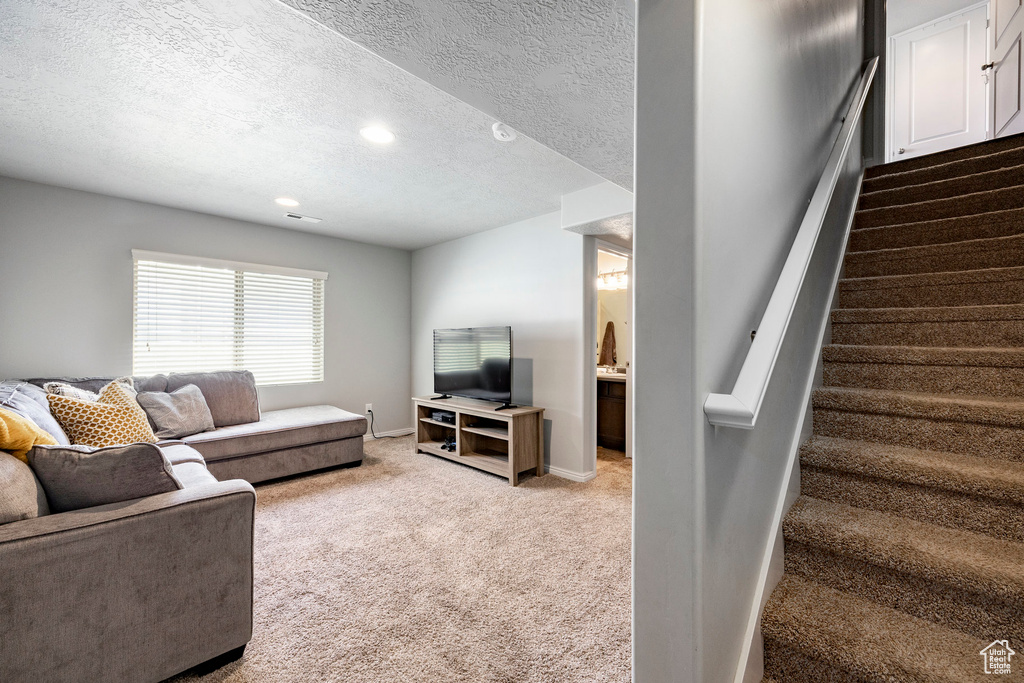 Living area with light carpet, stairs, recessed lighting, a textured ceiling, and baseboards
