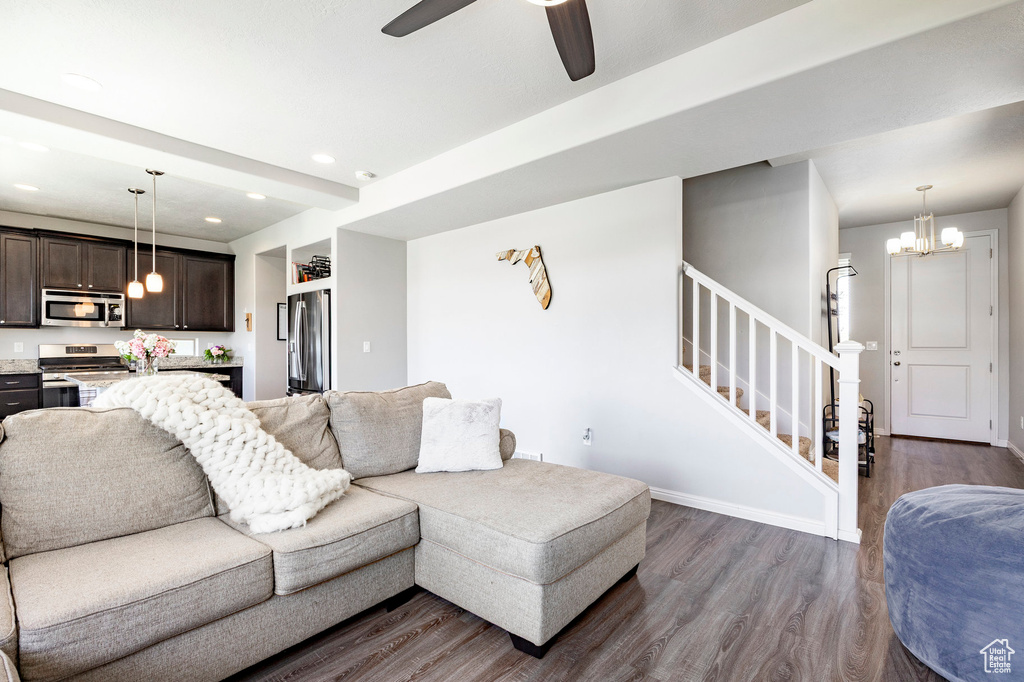 Living room featuring dark wood finished floors, a chandelier, stairs, ceiling fan, and recessed lighting