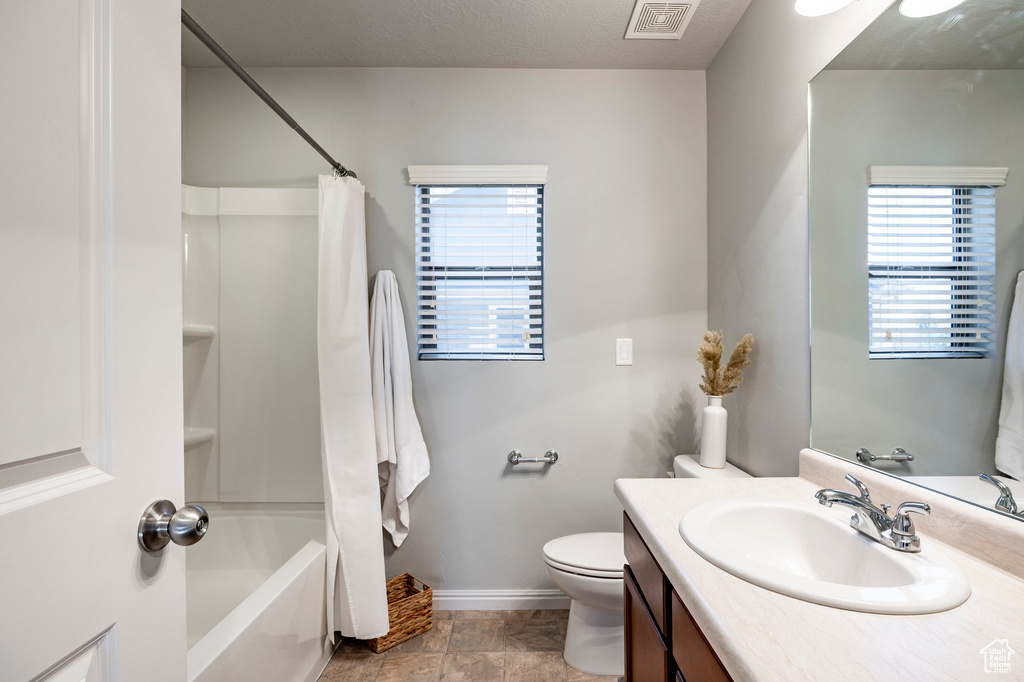 Bathroom with vanity, baseboards, toilet, and shower / bath combo