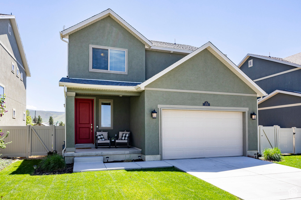 Traditional home featuring a gate, an attached garage, stucco siding, concrete driveway, and a porch