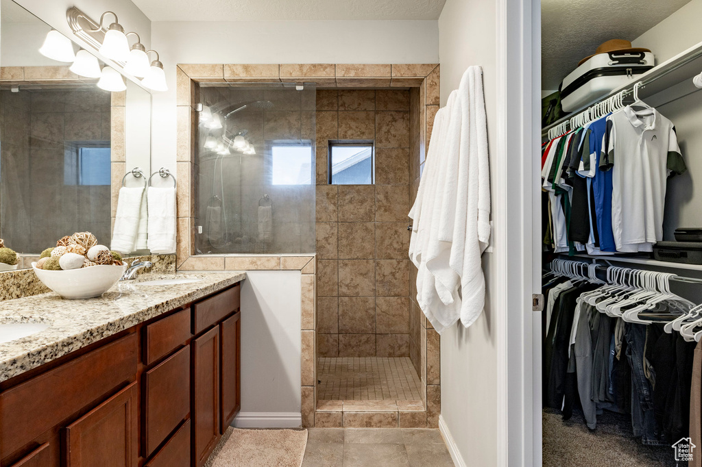 Full bath with a walk in shower, double vanity, and a spacious closet
