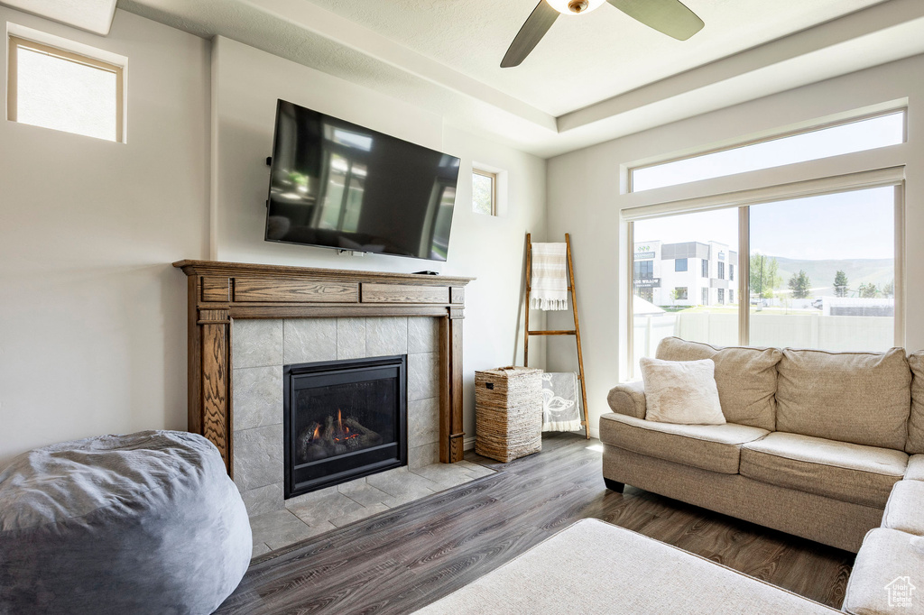 Living room featuring wood finished floors, a tile fireplace, and ceiling fan