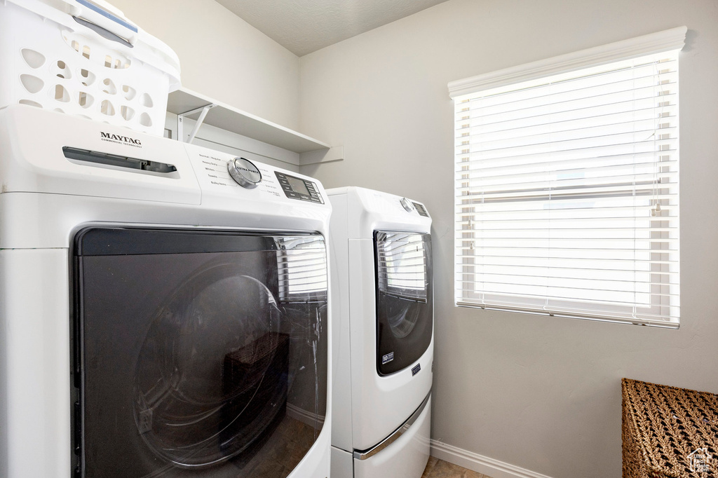 Washroom featuring separate washer and dryer, baseboards, and healthy amount of natural light