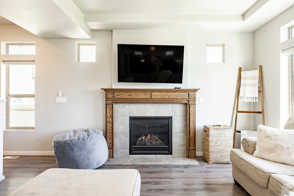 Living room with wood finished floors, a tile fireplace, and healthy amount of natural light