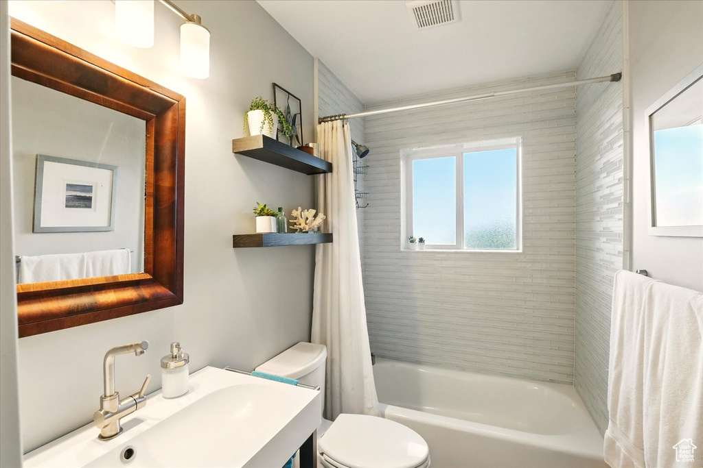 Full bath with toilet, shower / bathtub combination with curtain, and vanity
