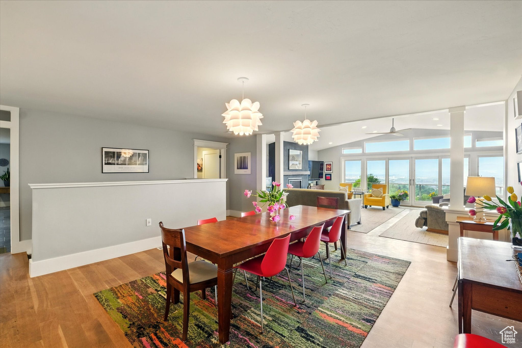 Dining space featuring lofted ceiling, a ceiling fan, light wood finished floors, a fireplace, and baseboards