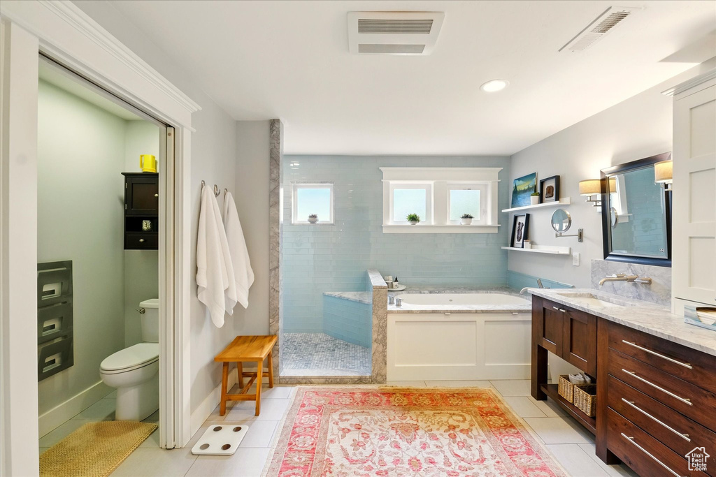Full bathroom with tile patterned flooring, a bath, a walk in shower, toilet, and vanity
