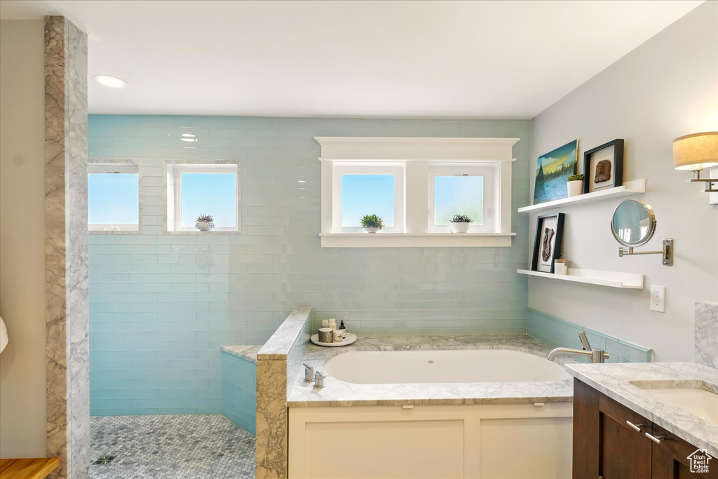 Bathroom featuring a walk in shower, a bath, and vanity
