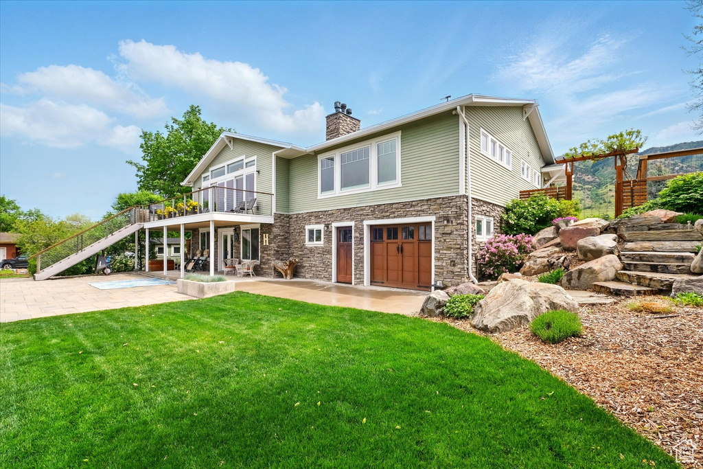 Rear view of house with stairs, a patio area, stone siding, and a yard