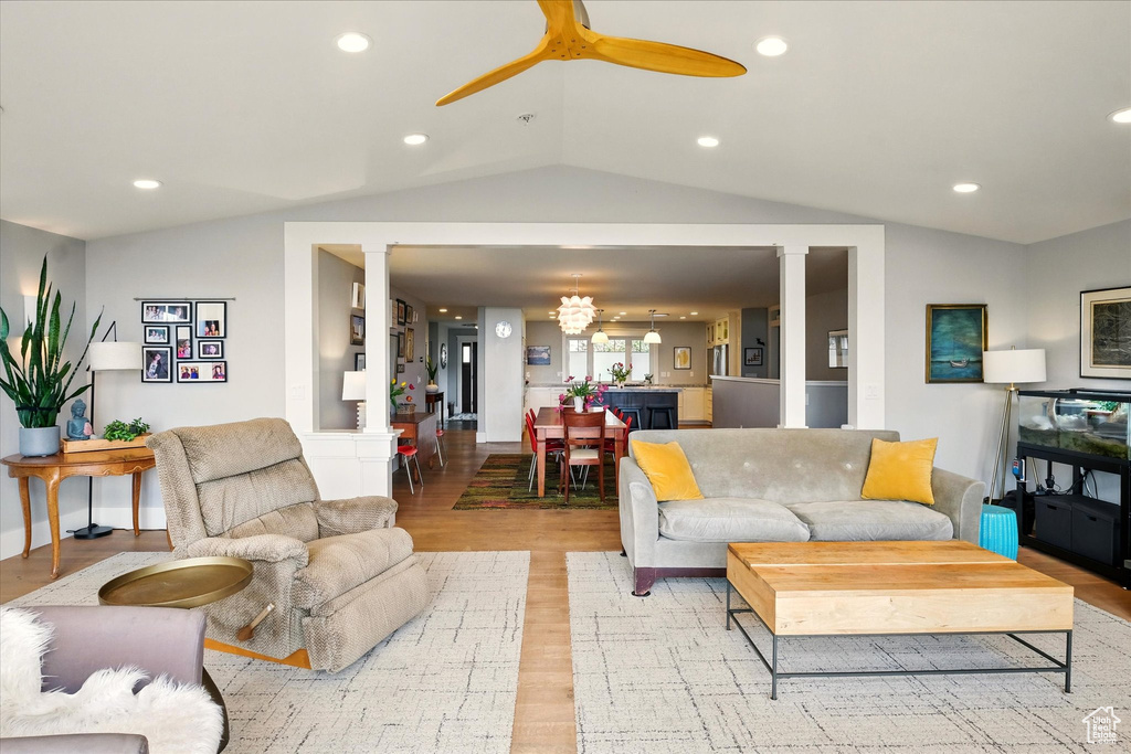 Living area with vaulted ceiling, ornate columns, light wood-style floors, ceiling fan, and recessed lighting