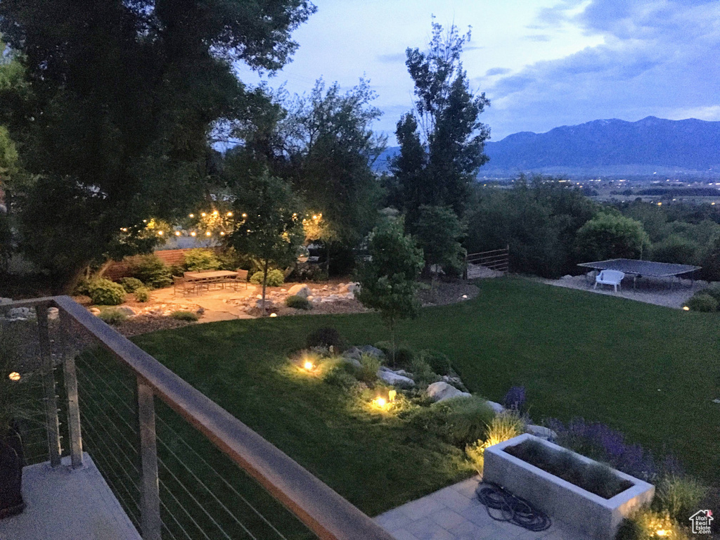 View of green lawn featuring a patio and a mountain view