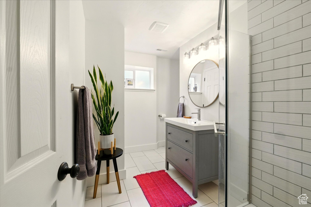 Full bathroom with a shower stall, vanity, tile patterned floors, and baseboards