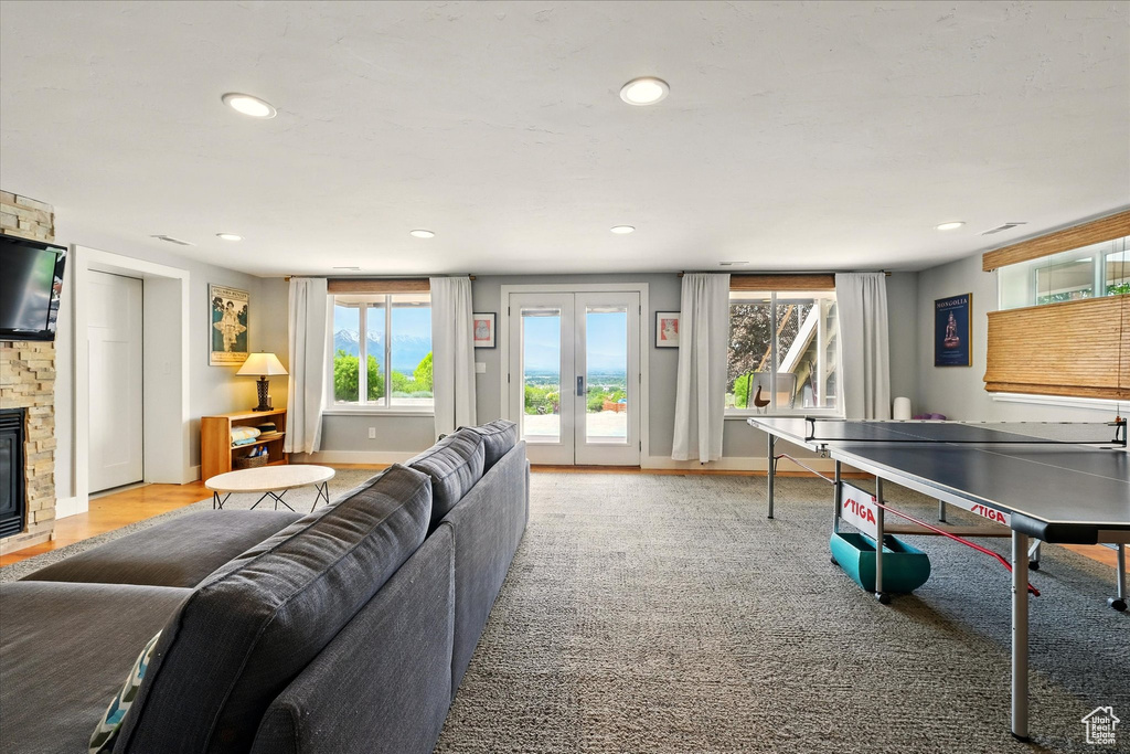 Recreation room with healthy amount of natural light, a stone fireplace, recessed lighting, and french doors