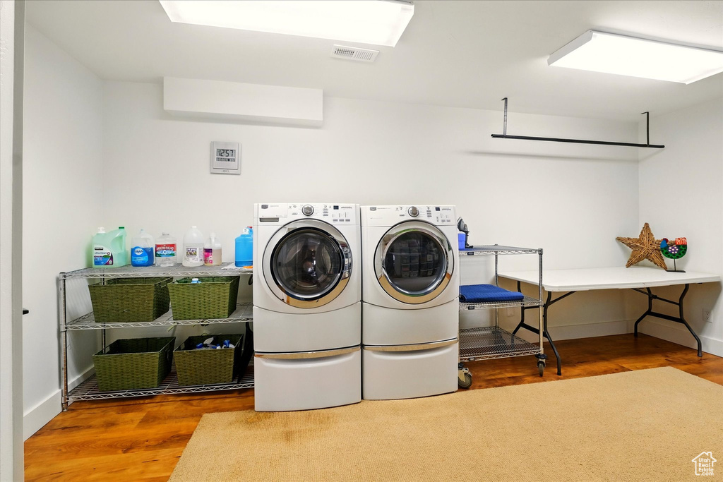 Laundry area with wood finished floors, separate washer and dryer, and baseboards