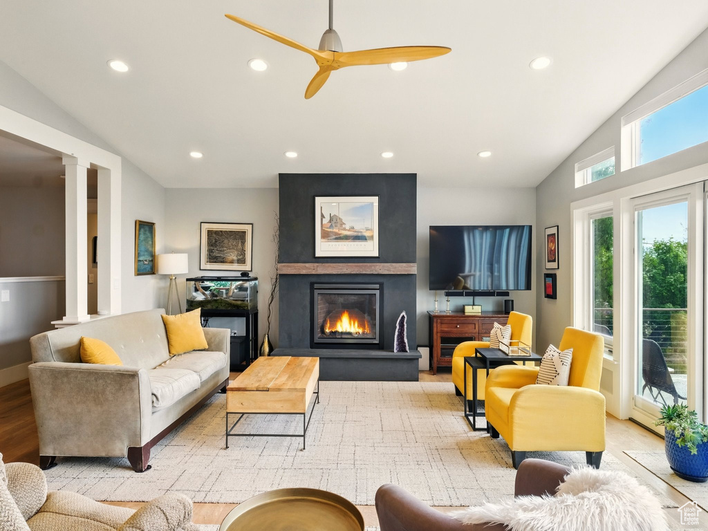 Living area with lofted ceiling, a fireplace, ceiling fan, ornate columns, and recessed lighting