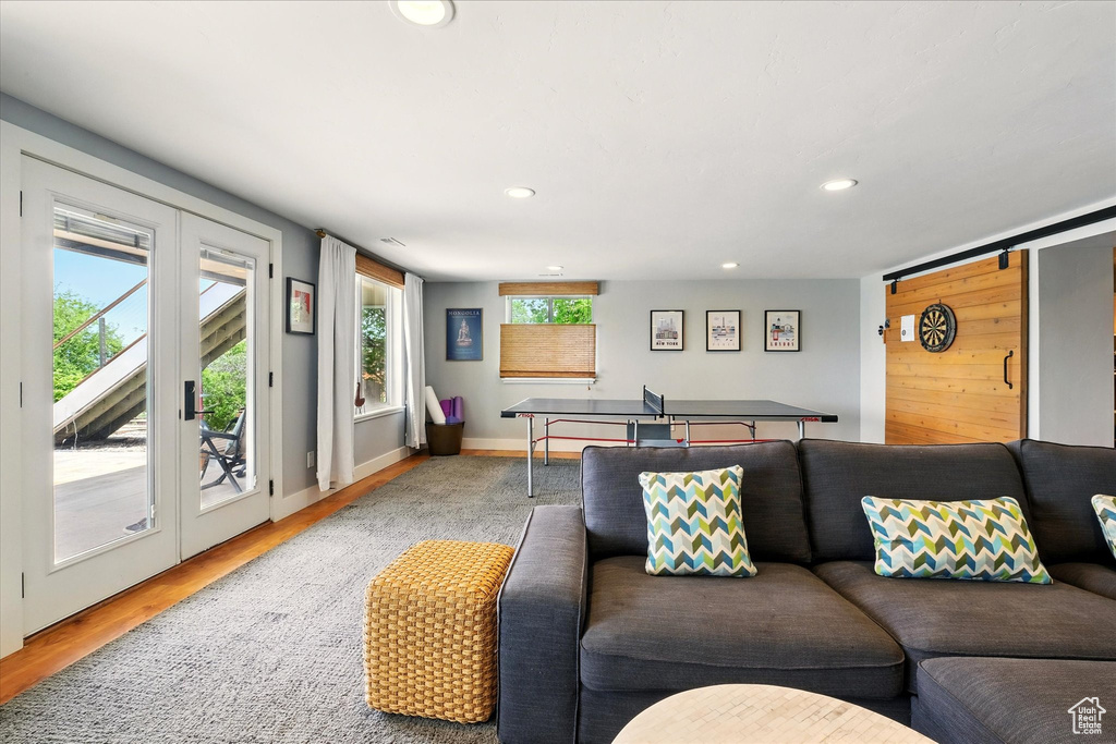 Living room featuring recessed lighting, wood finished floors, a barn door, and baseboards
