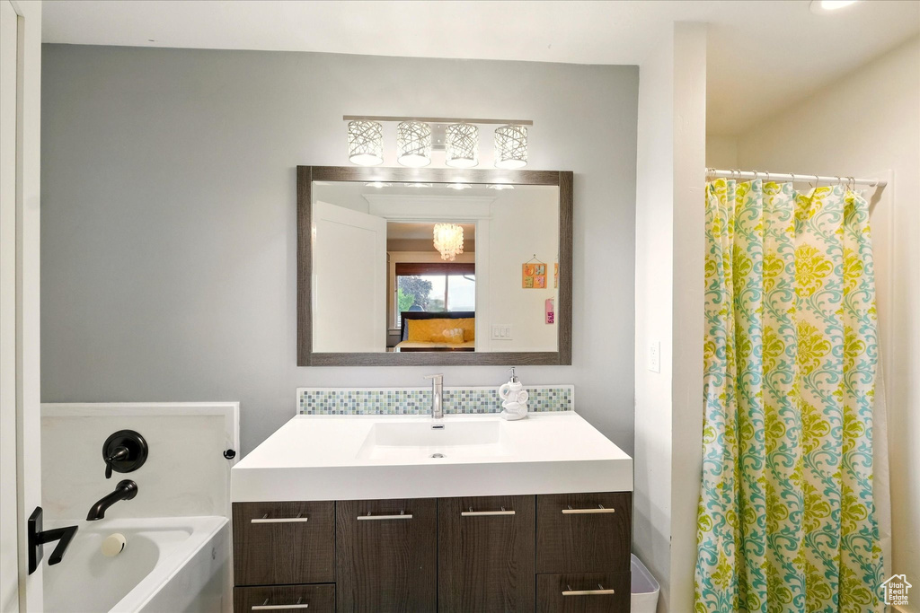 Full bath featuring vanity, a bathtub, a shower with curtain, and tasteful backsplash