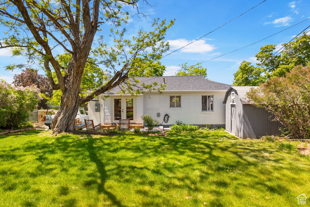 Back of house featuring french doors, an outbuilding, a storage unit, and brick siding